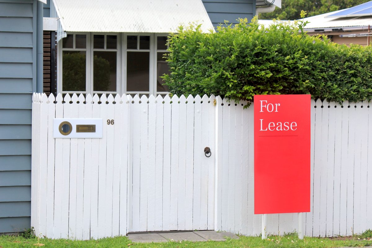red for lease sign on white picket fence