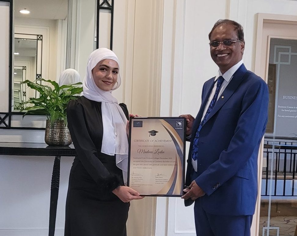 Womann in hijab receives a certificate from a man.