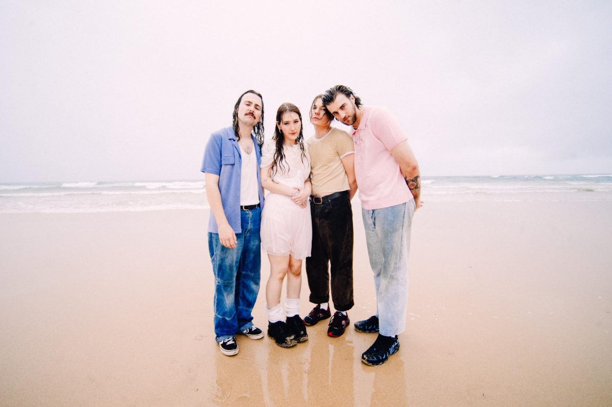 two men and two women standing on a beach in the rain