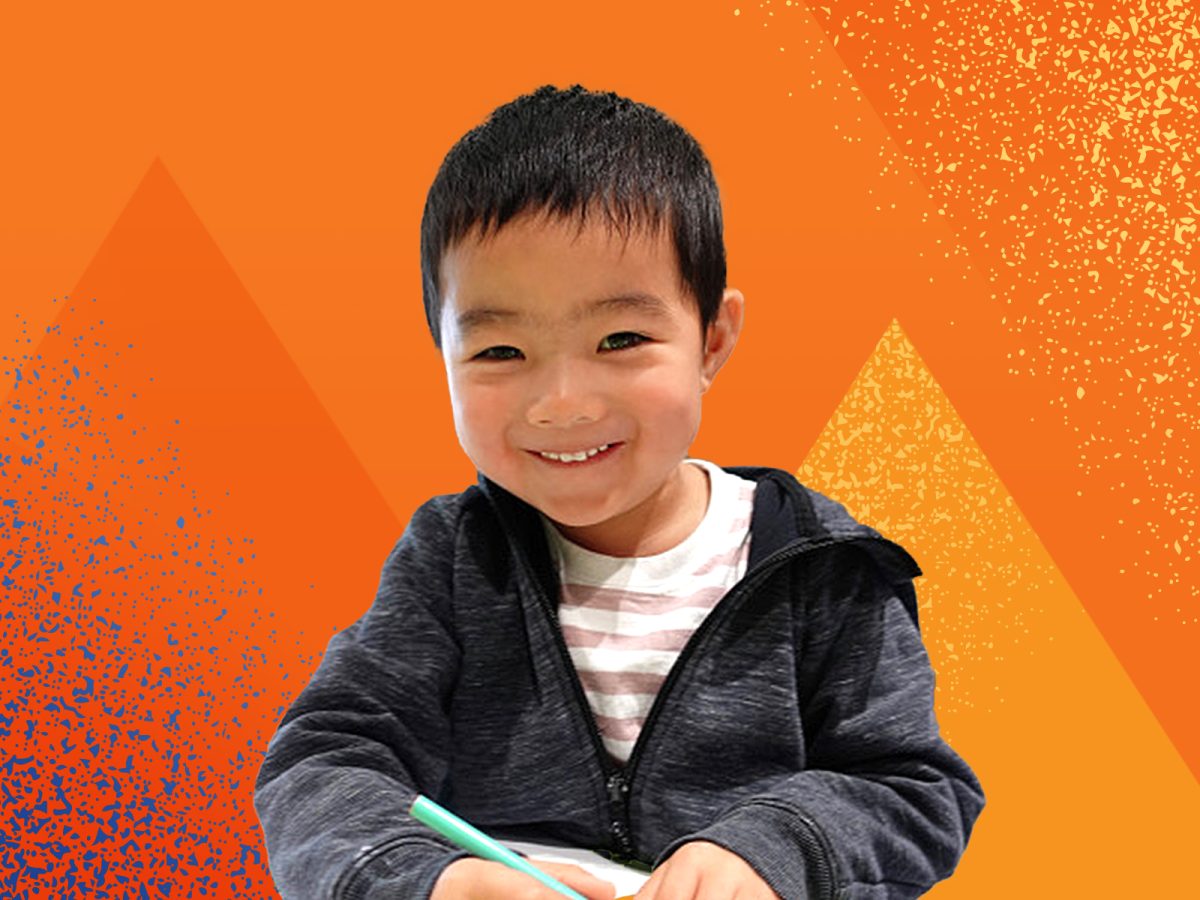 Photo of a young boy enjoying a craft activity against an orange stylised pyramid background