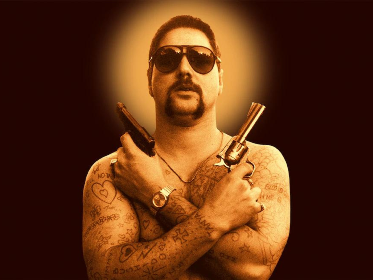 Image from the Chopper poster showing a tattooed man holding two guns across his chest