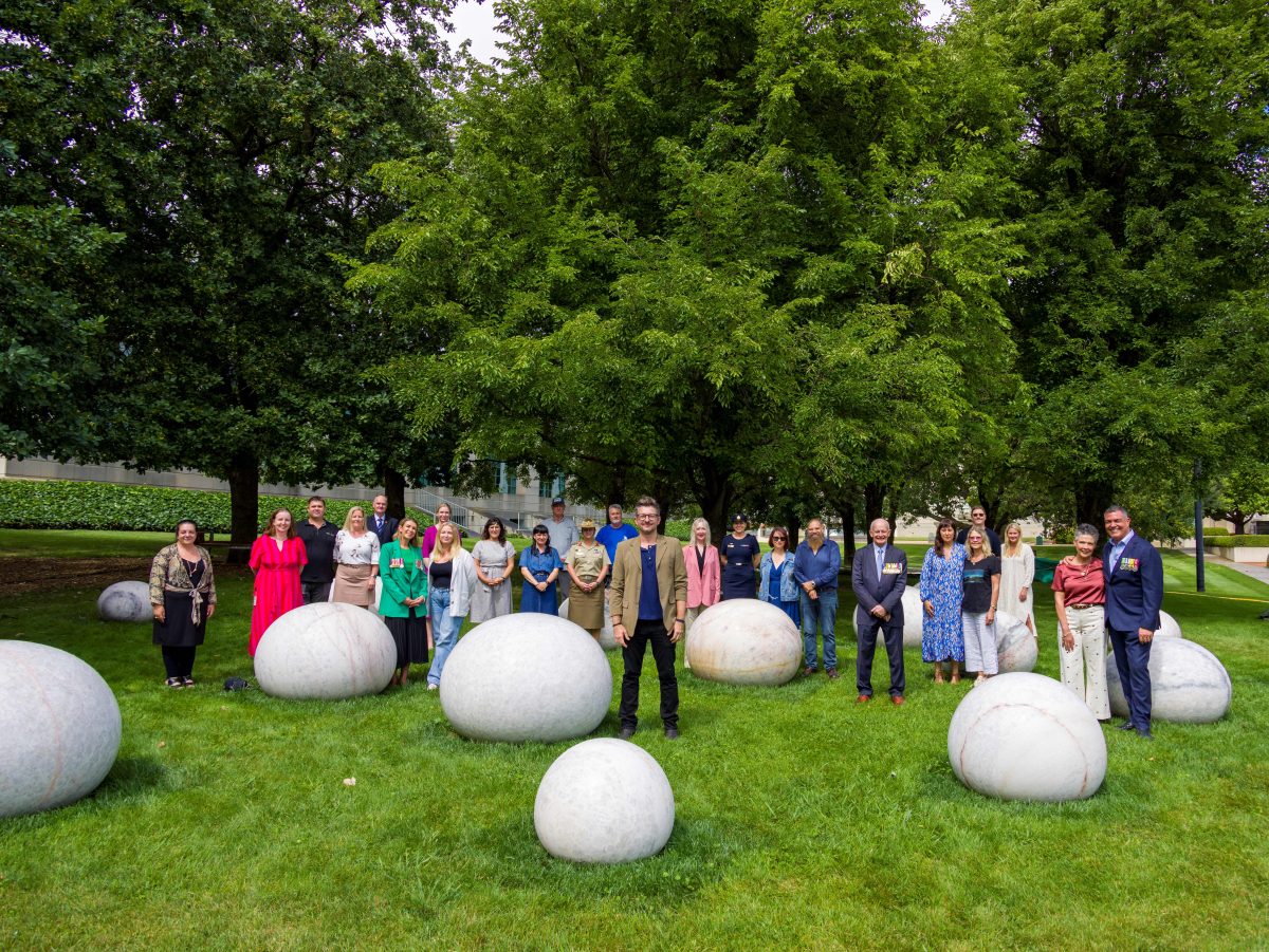 Man standing in front of sculpture with people in background