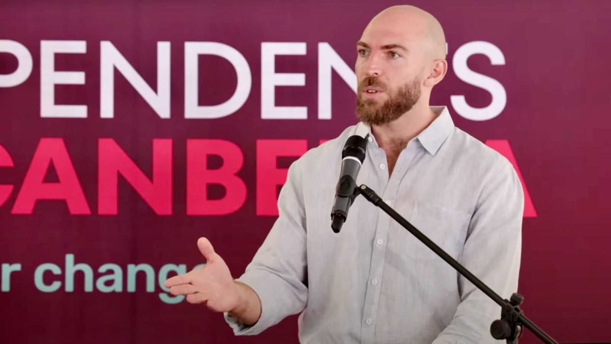 Man standing and speaking into a microphone