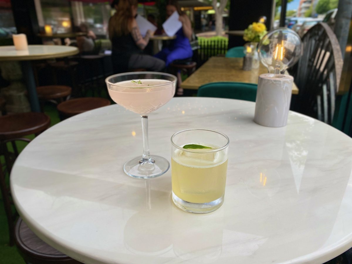 Two cocktails on a marble high top table.