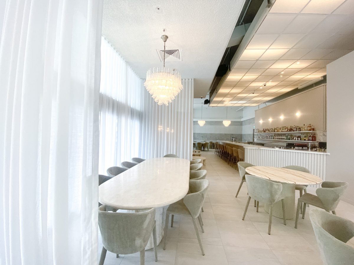 White table with quirky glass light fitting and white curtains.