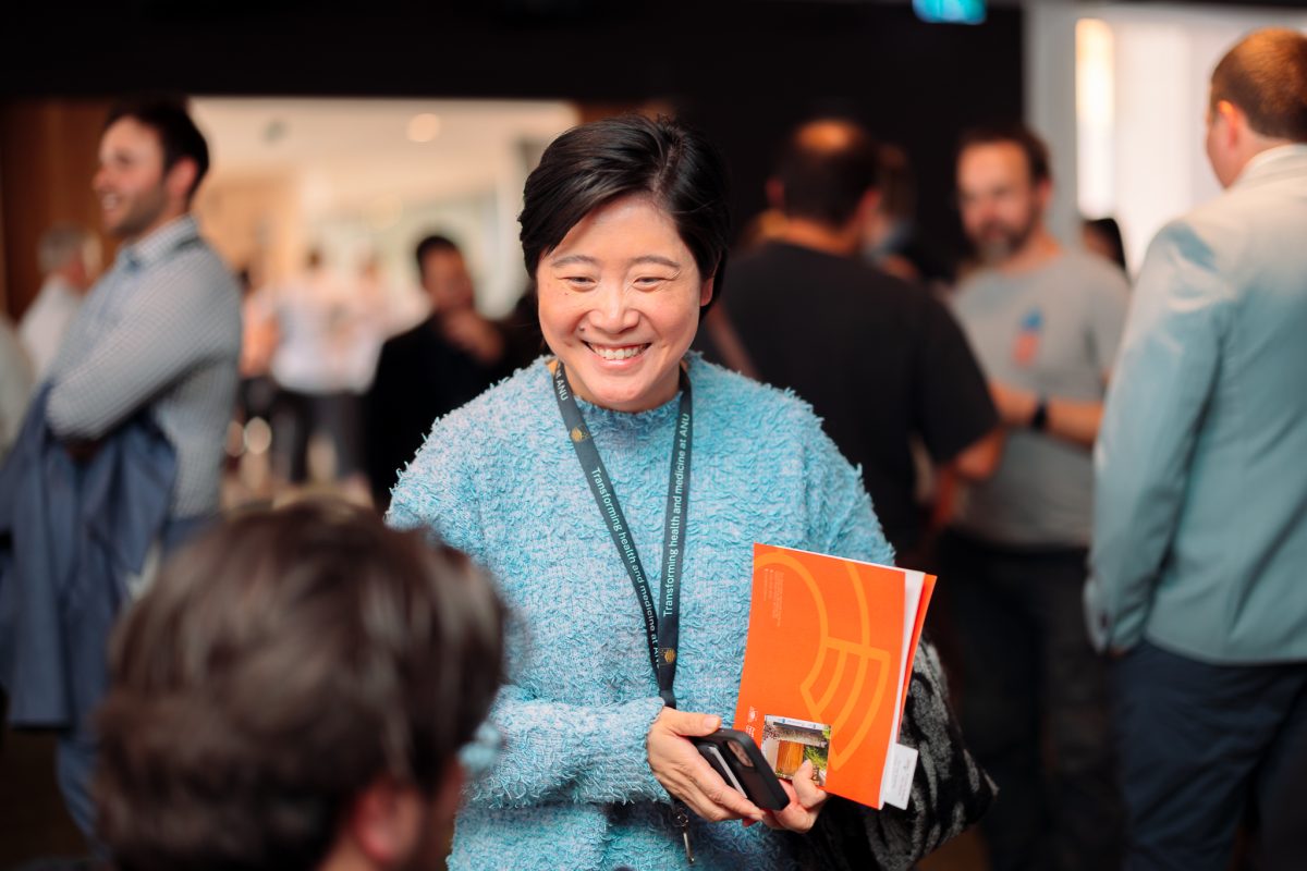 woman smiling and holding book at networking event