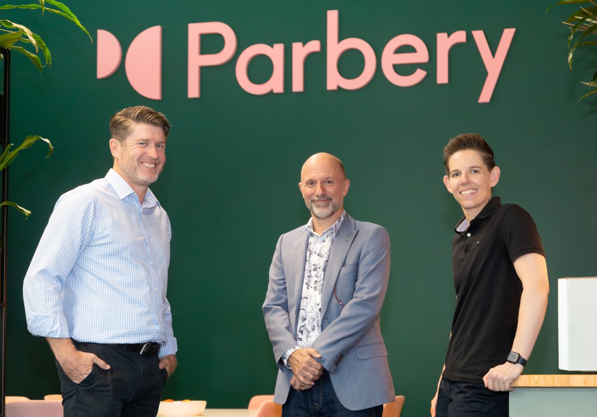 Three adults standing under 'Parbery' sign