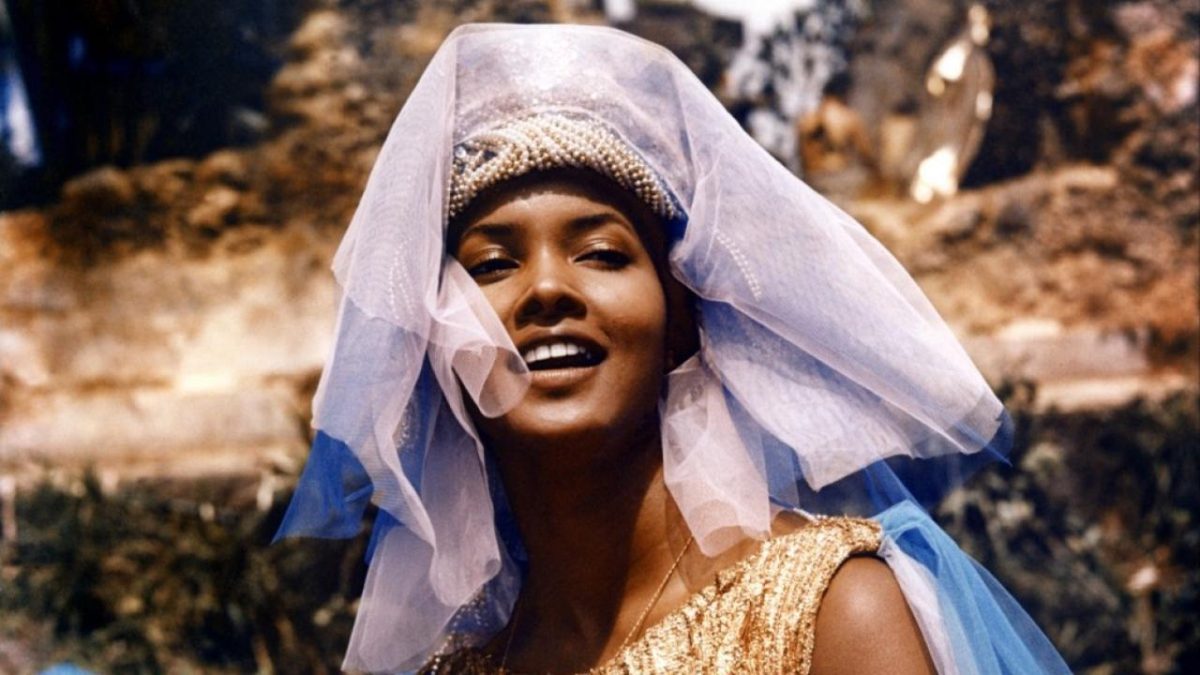 Still from Black Orpheus showing a close up of a woman wearing a purple headdress