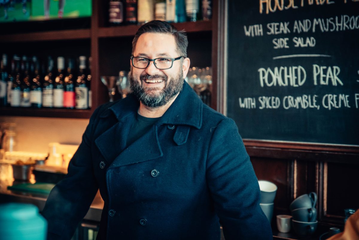 A man in a dark coat and glasses