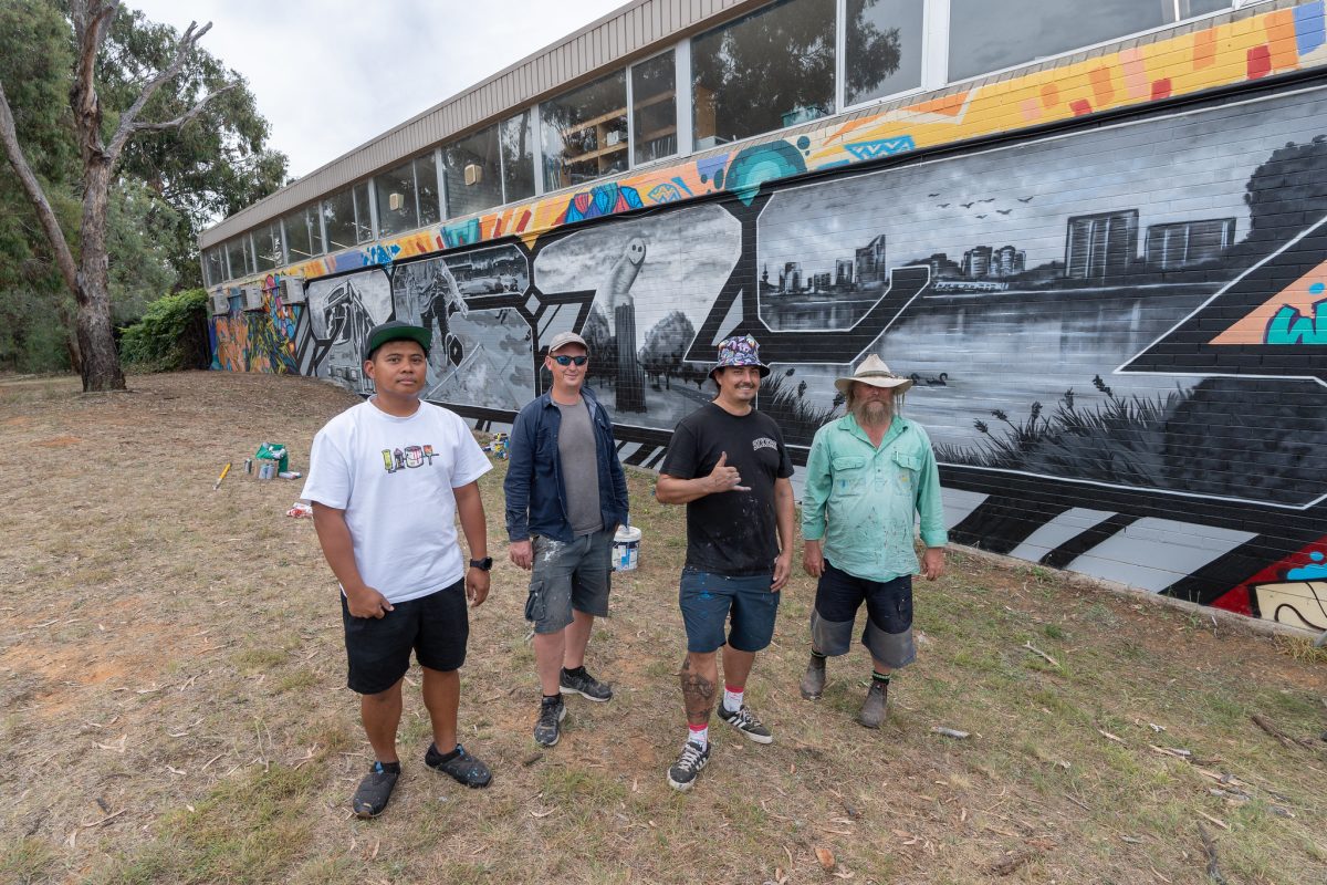 four men in front of a mural