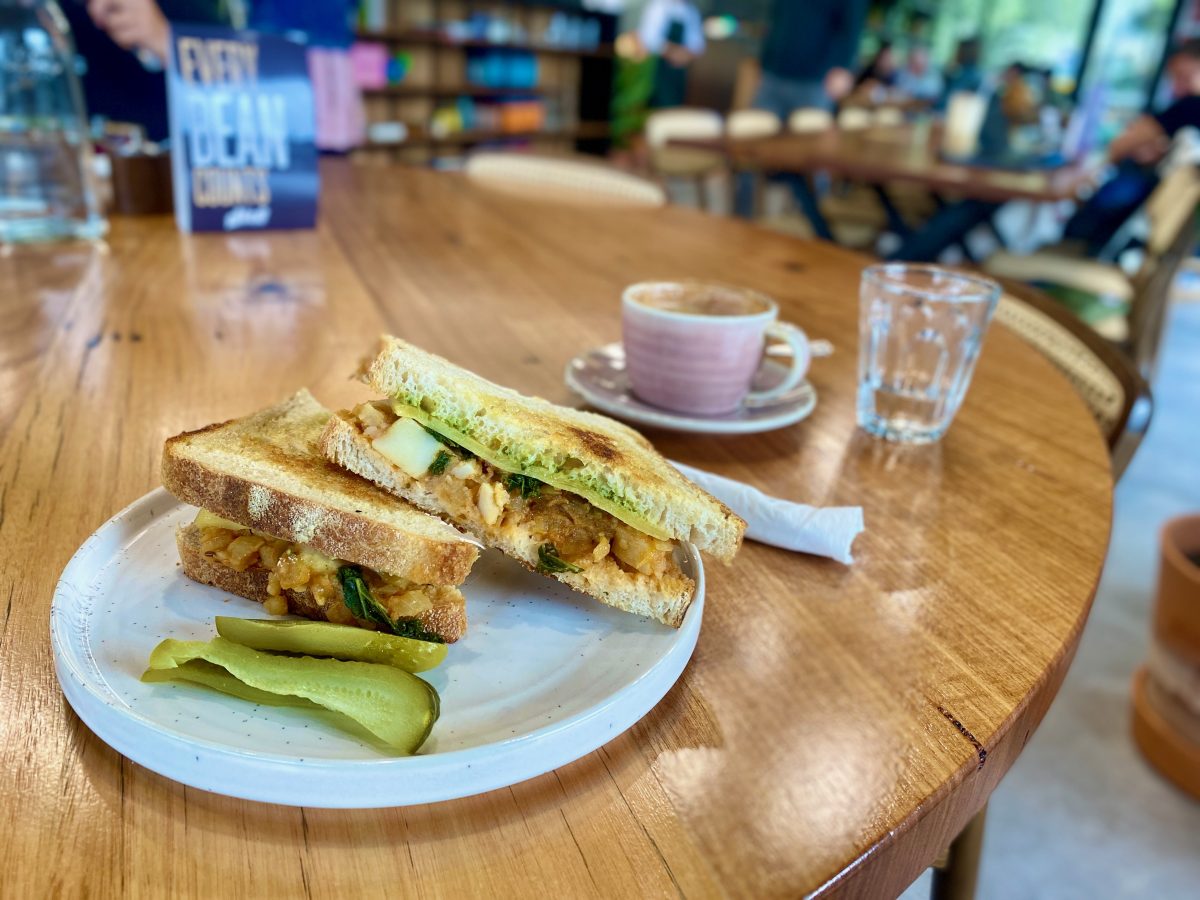 Hearty toastie with pickles and a pink coffee cup.
