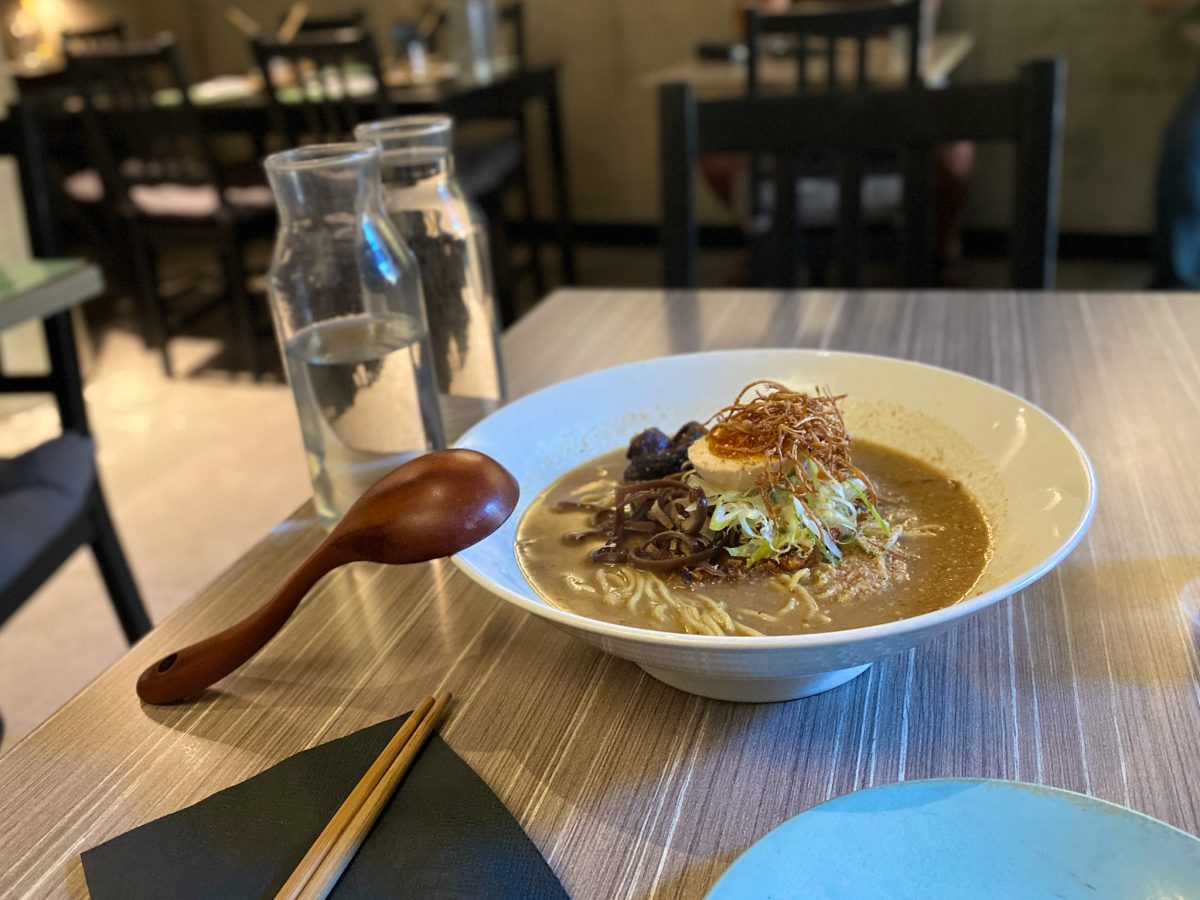 Bowl of ramen with half egg and wooden spoon