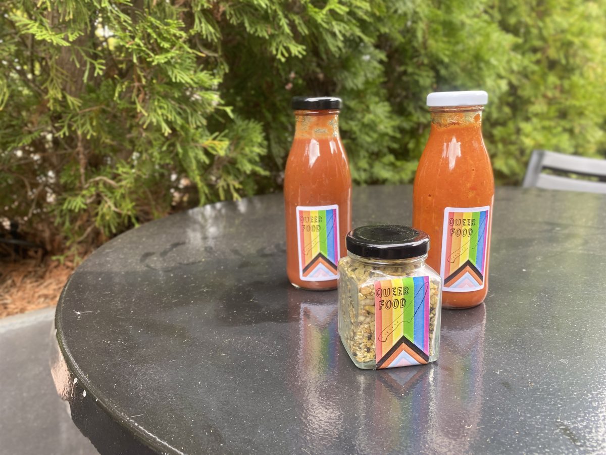 Two bottles of sauce and a jar of dukkah with rainbow Queer Food branded labels.