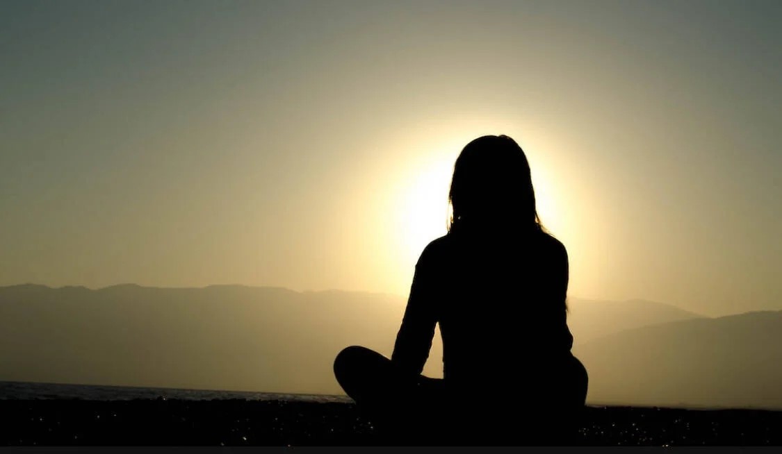 Silhouette of someone sitting looking at sun 