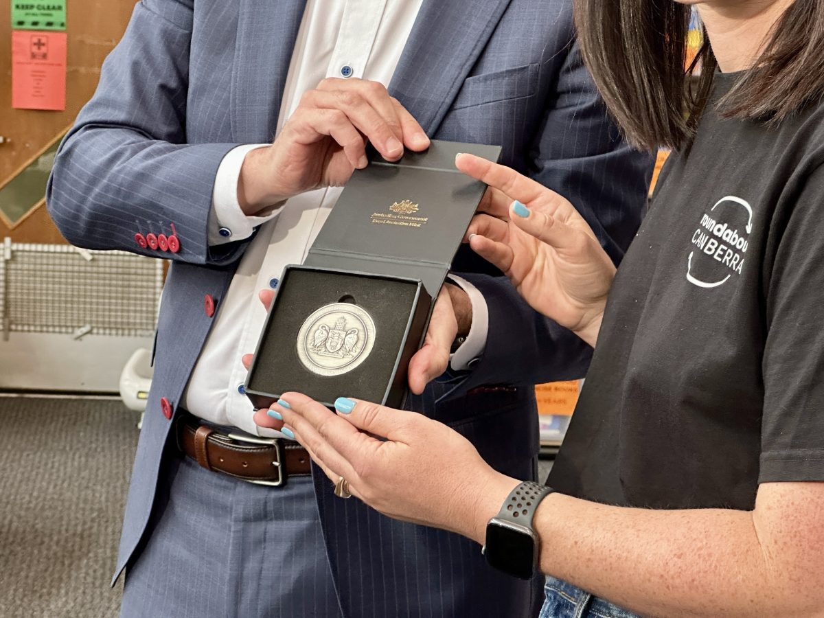 hands holding a medal in a display box