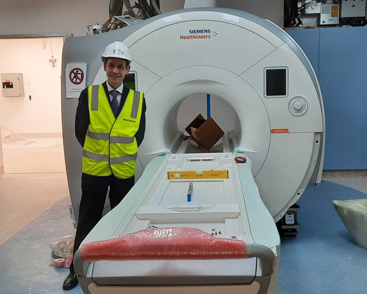 man stabding next to an MRI machine