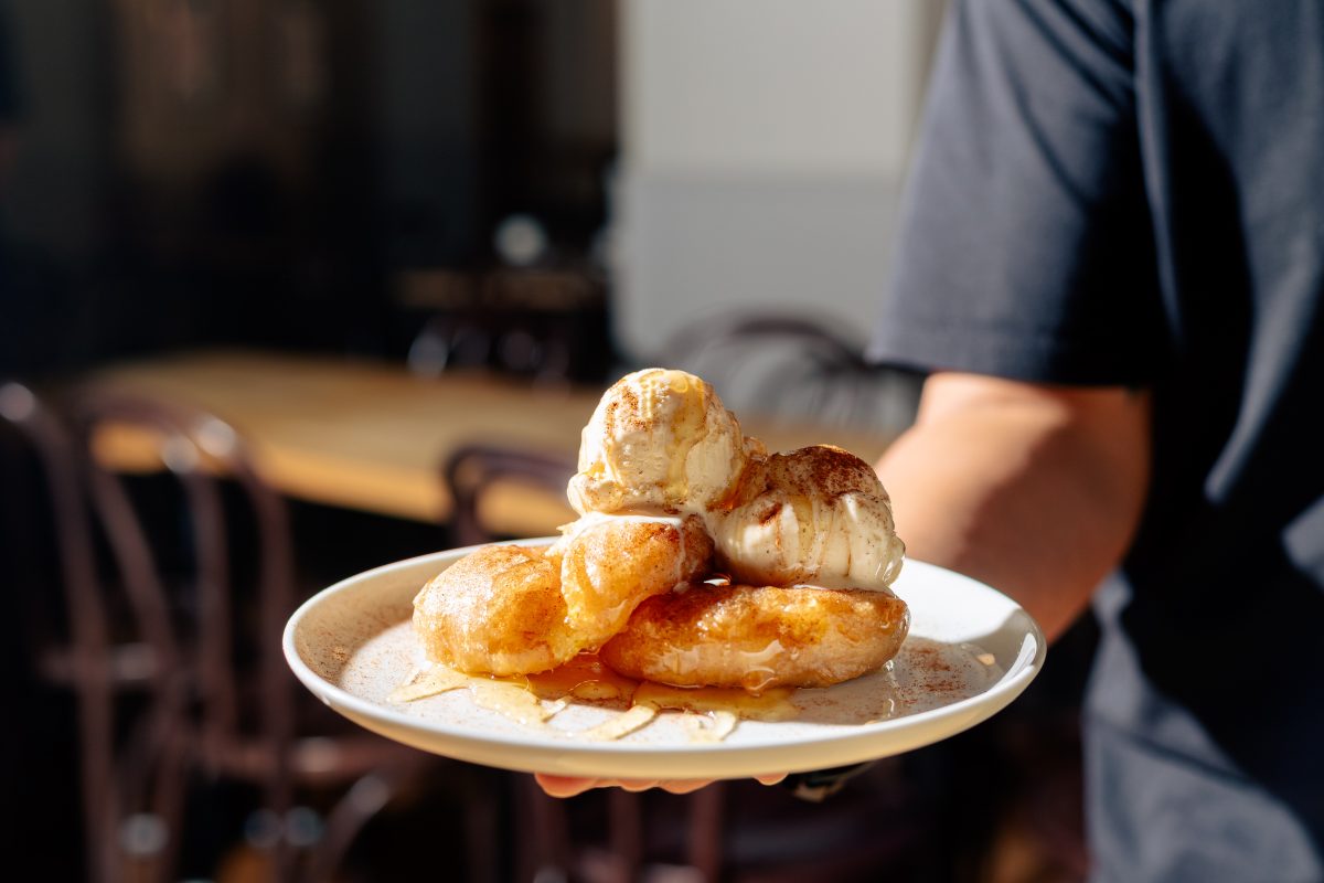 Plate of delicious looking fritters with scoops of icecream.