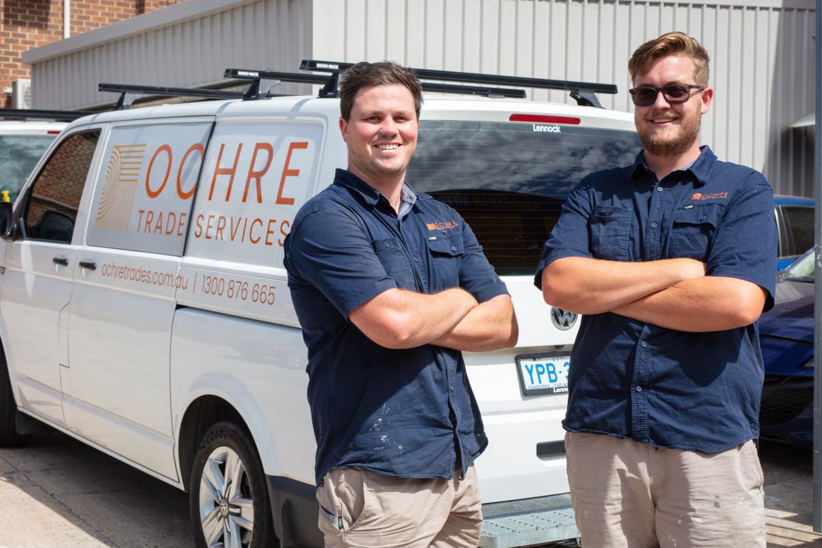two trades people standing in front of a van