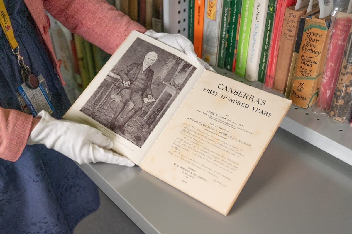 White gloved hands holding old book