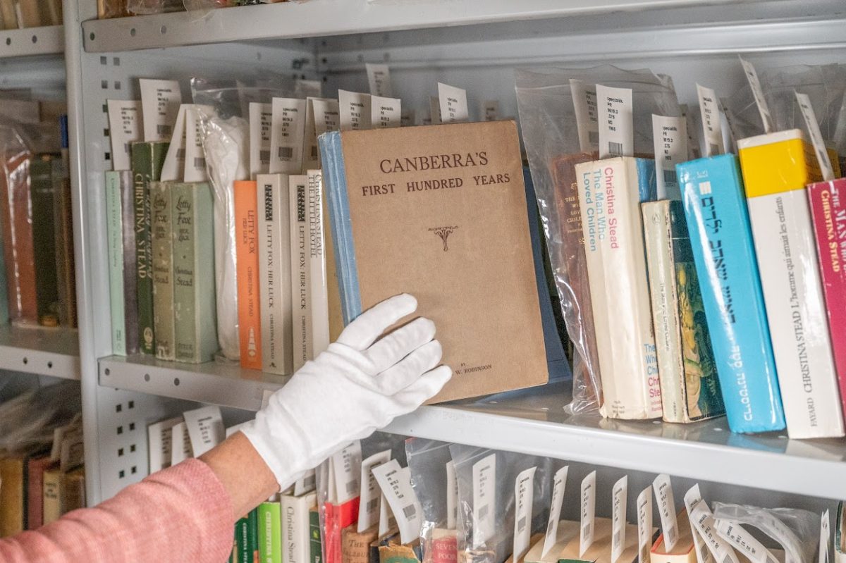 Gloved hand with old book on bookshelf