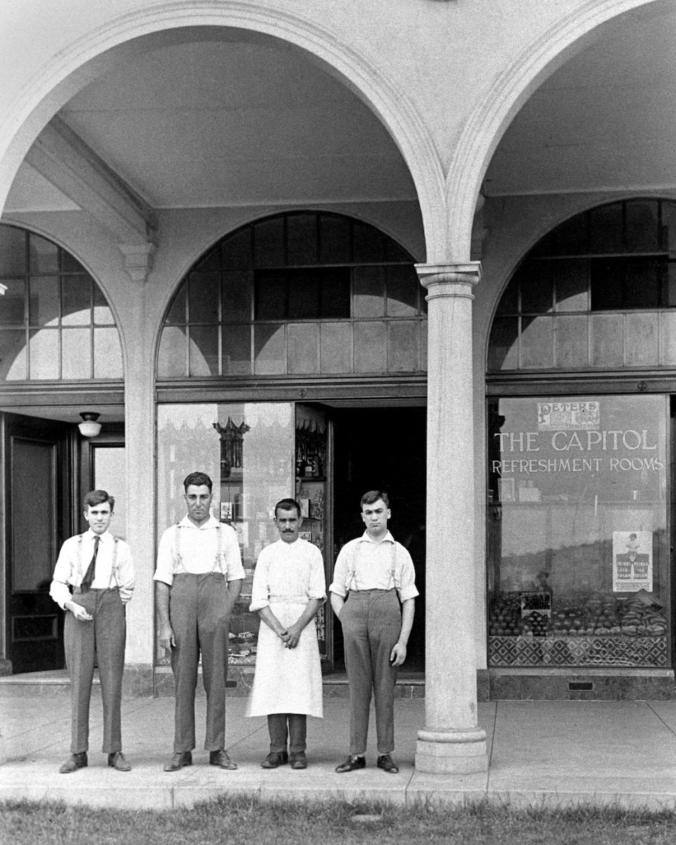 Four men standing outside the arches of Capitol Refreshment Rooms in East Row, Civic