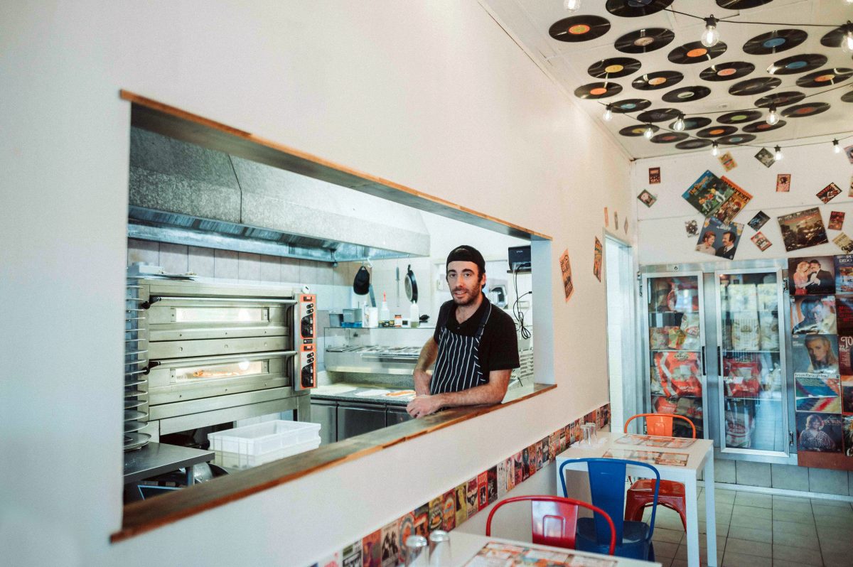 man leaning on counter in pizza shop