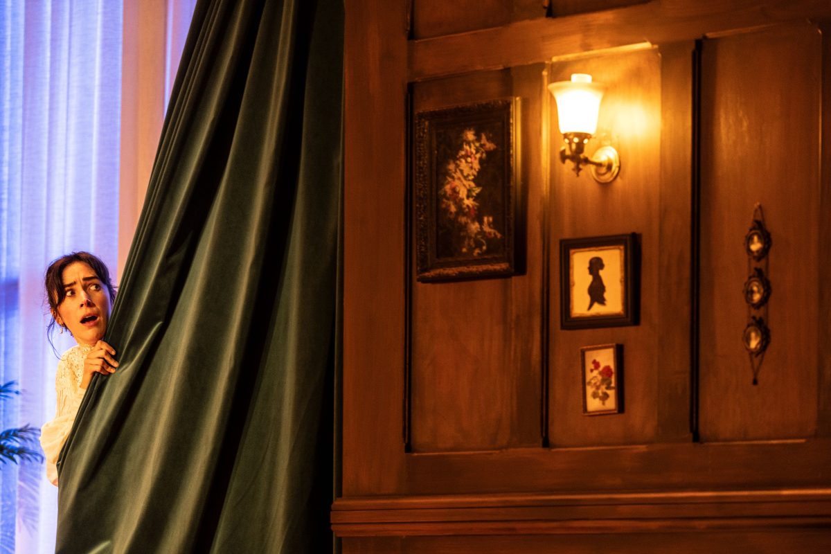 A scared woman leaning out from behind a curtain to look a light