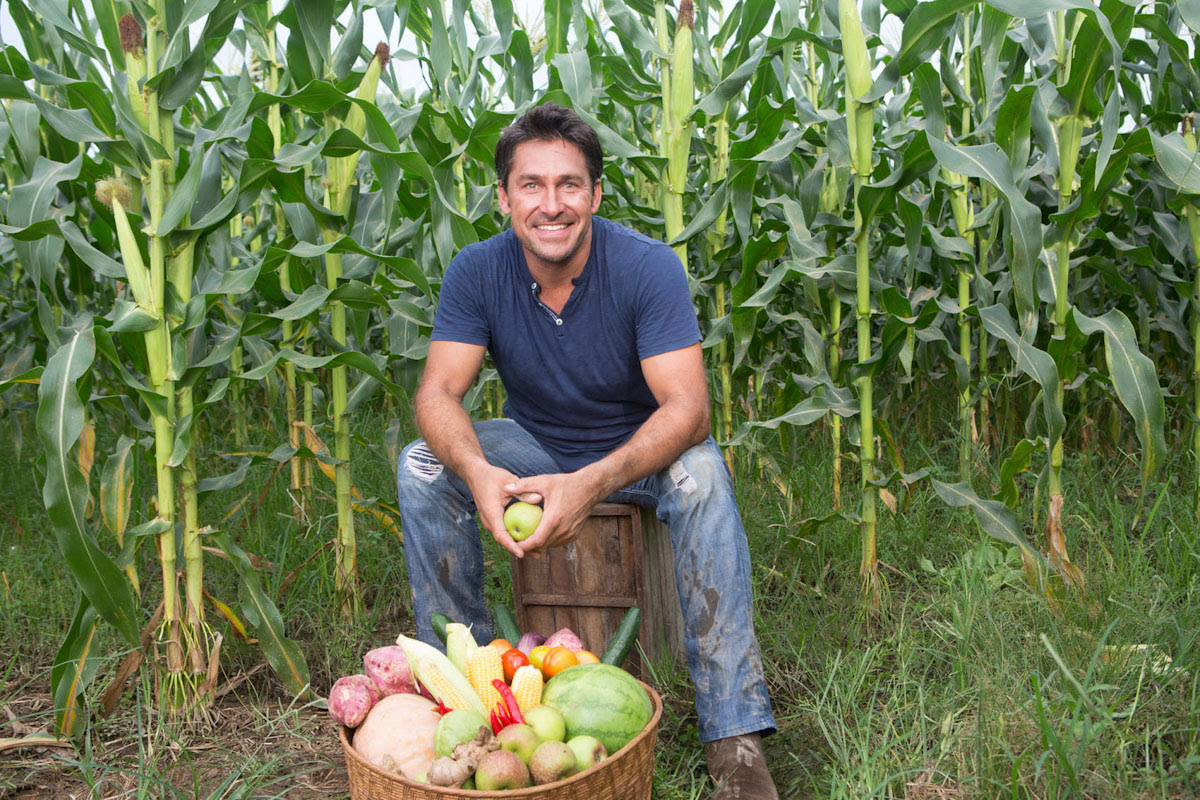 A man sitting in a field with a basket of produce