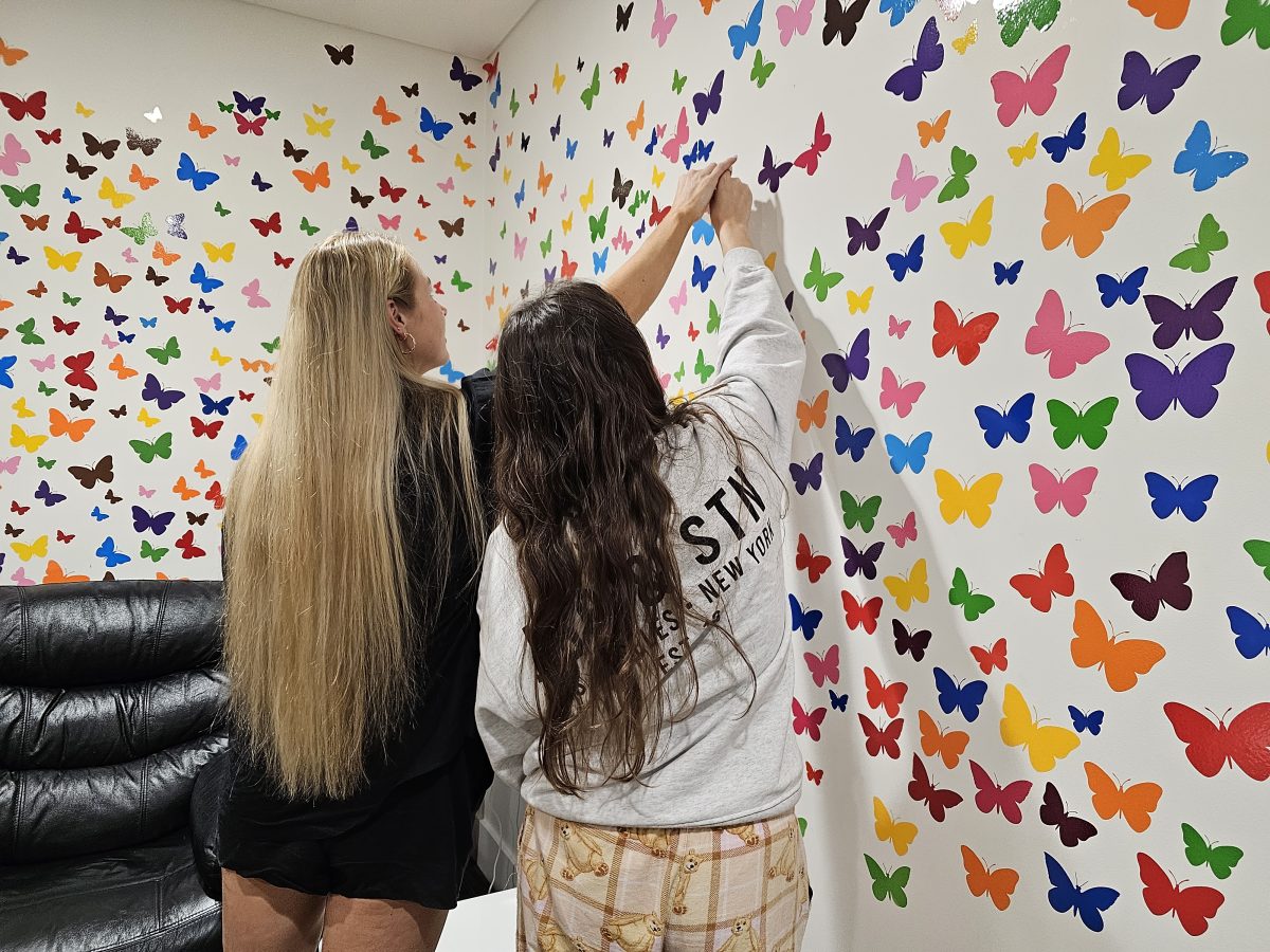 Brittany Wilkinson placing a coloured butterfly on the wall