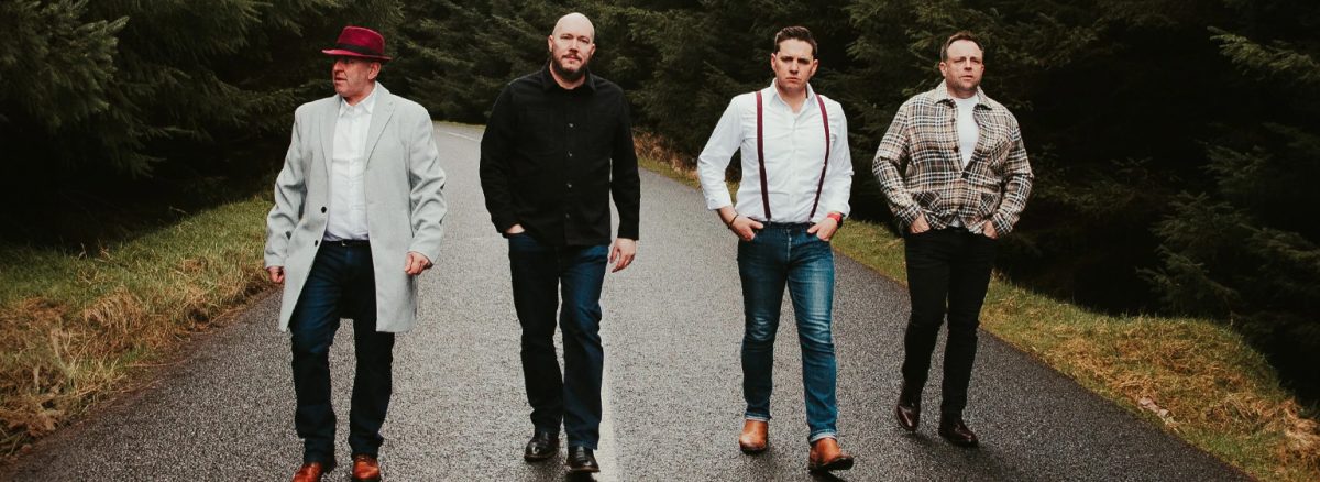 Four men walking in a line towards the camera