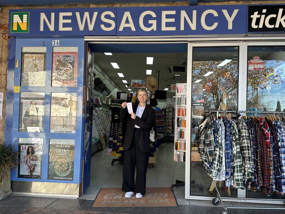 woman standing outside newsagent with powerball ticket