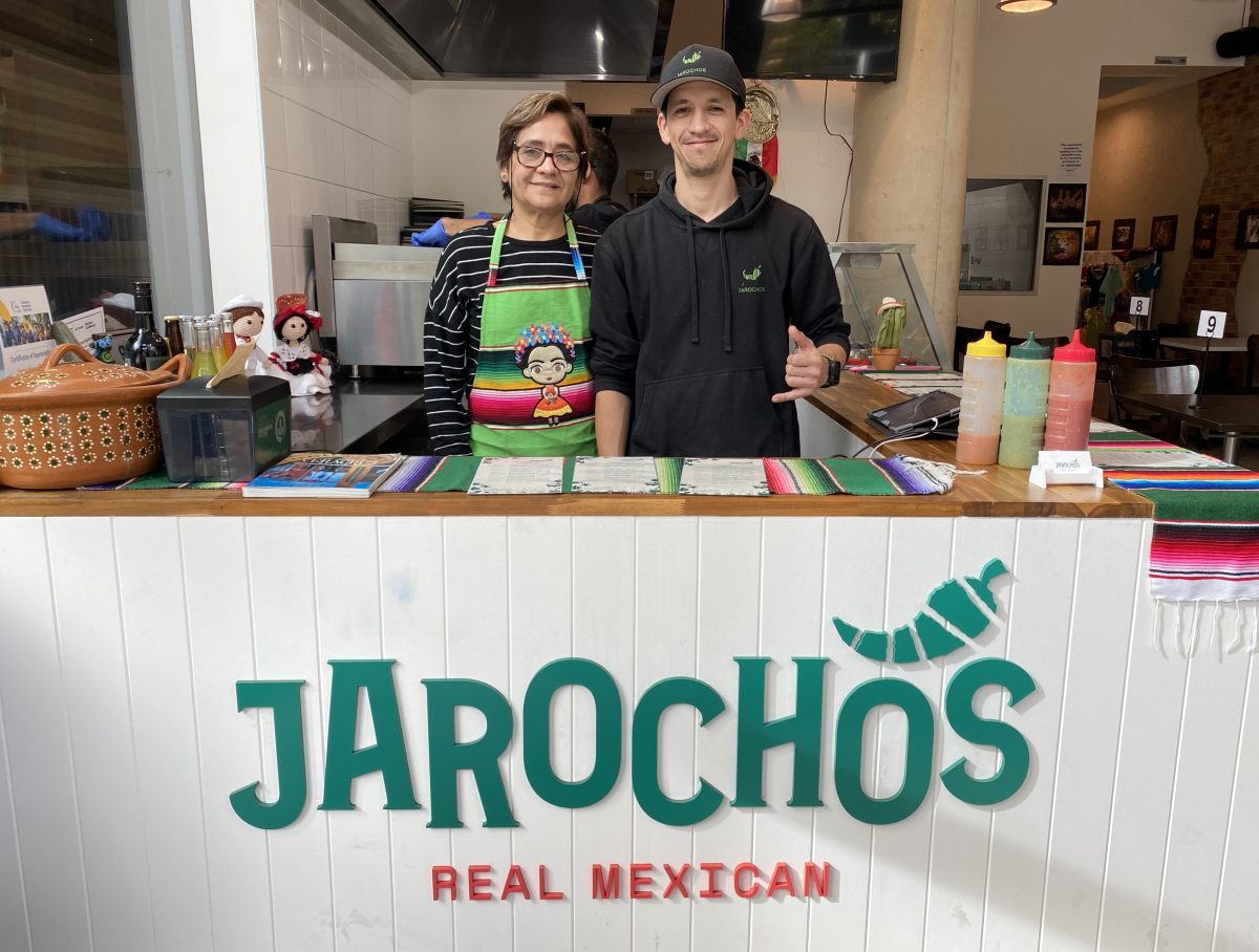 Cesar and his mum, wearing a colourful apron, behind the counter at Jarochos. 