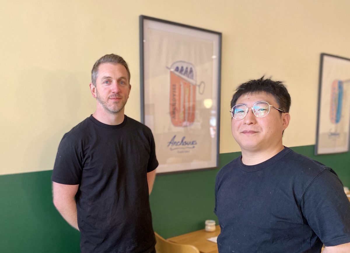 Max and Nicky stand in front of print with anchovies.