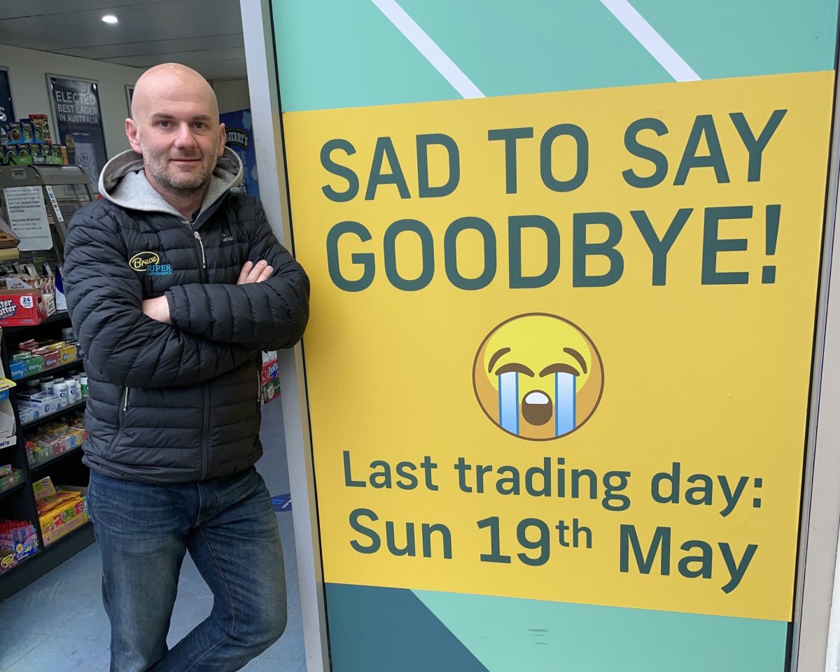 shopkeeper Dejan standing next to a sign