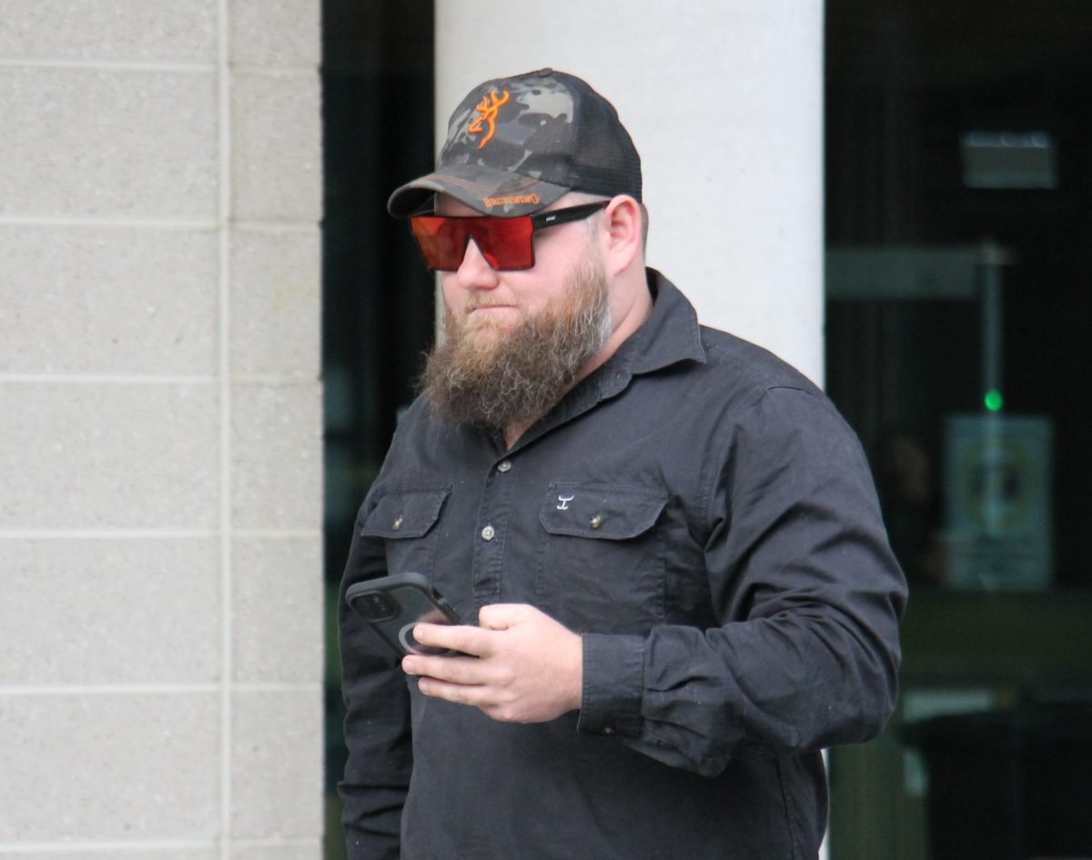 man outside court with a cap and phone