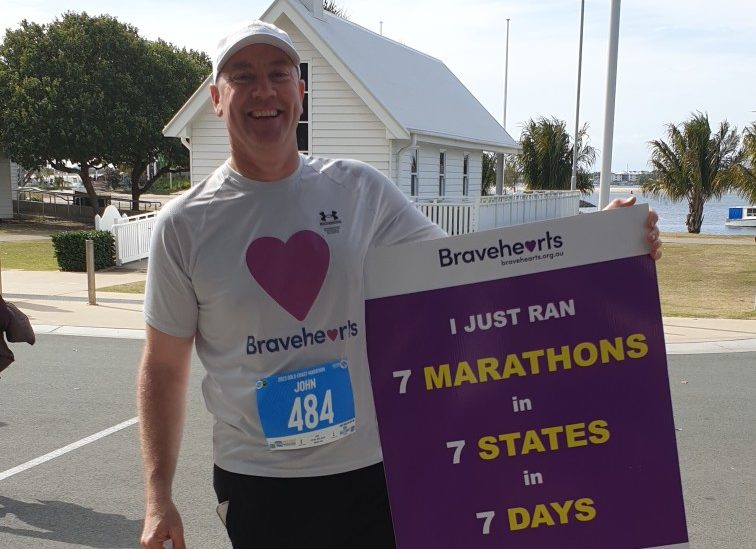 John Wilson holds a sign showing off his achievements. 