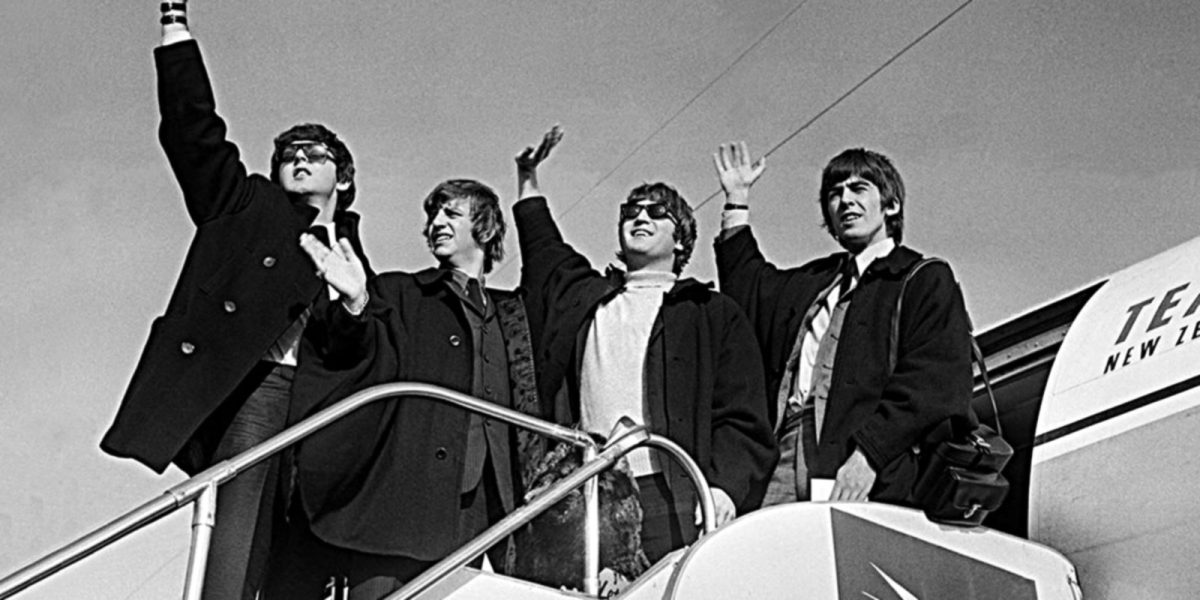 Black and white image of The Beatles waving from a plane