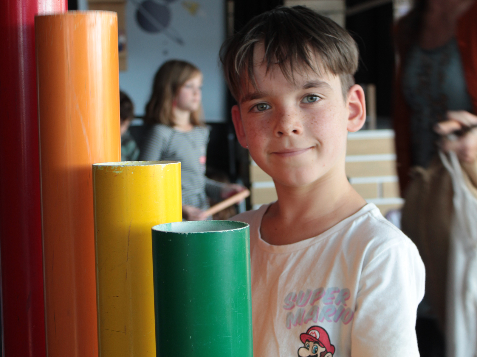 Boy standing beside rainbow pipes
