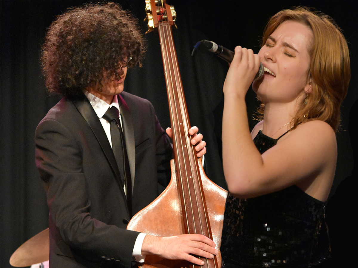 Young man with curly hair playing cello and young lady singing