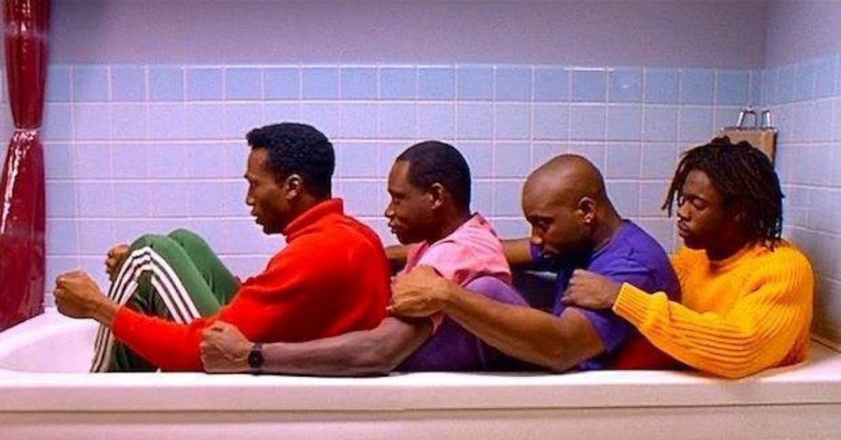 Four men sitting clothed in a bathtub as though in a bobsled