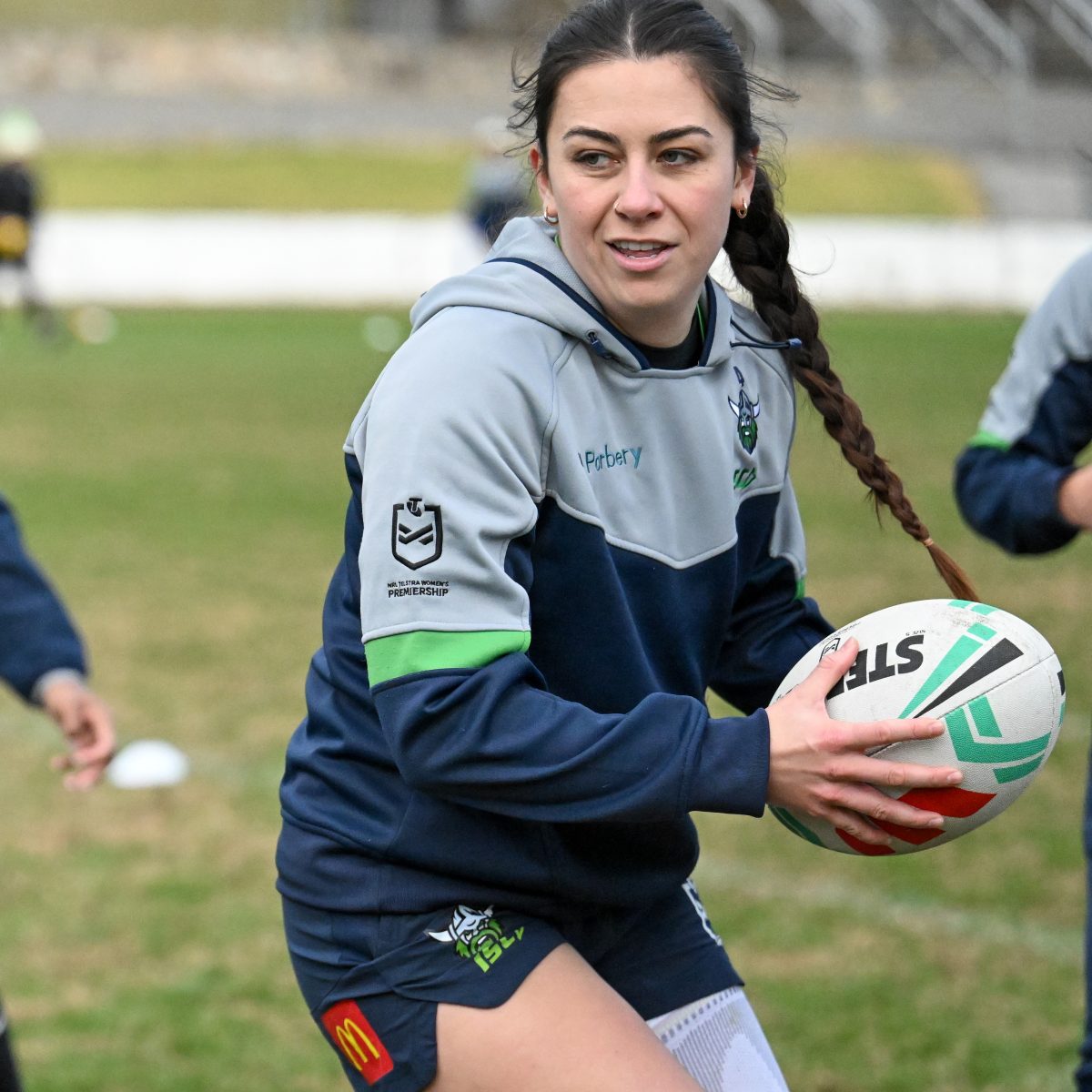 A lady holding a Rugby League ball.