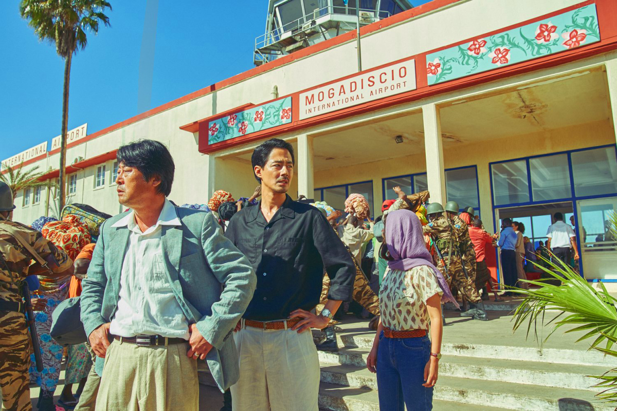 Still from Escape To Mogadishu showing a group of people outside an airport