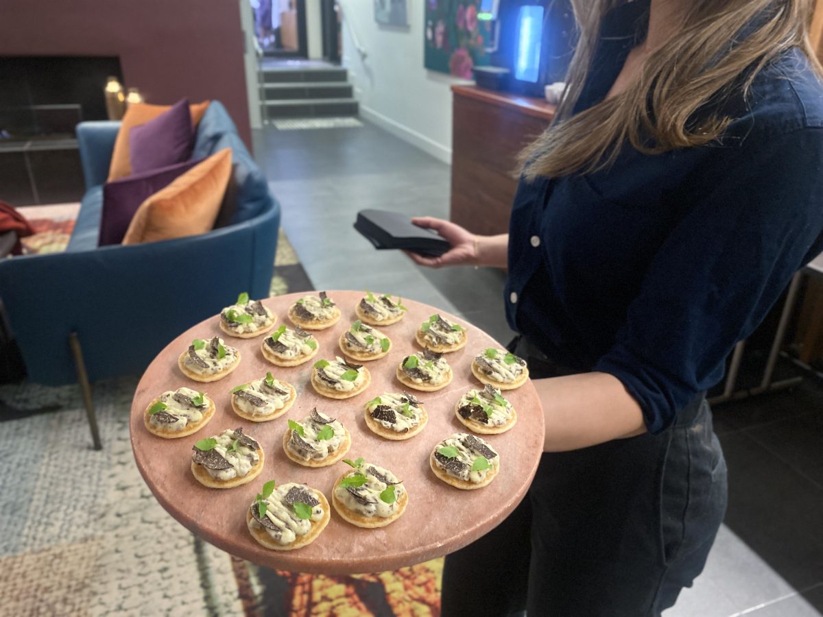 Waiter holding platter of truffle canapes.