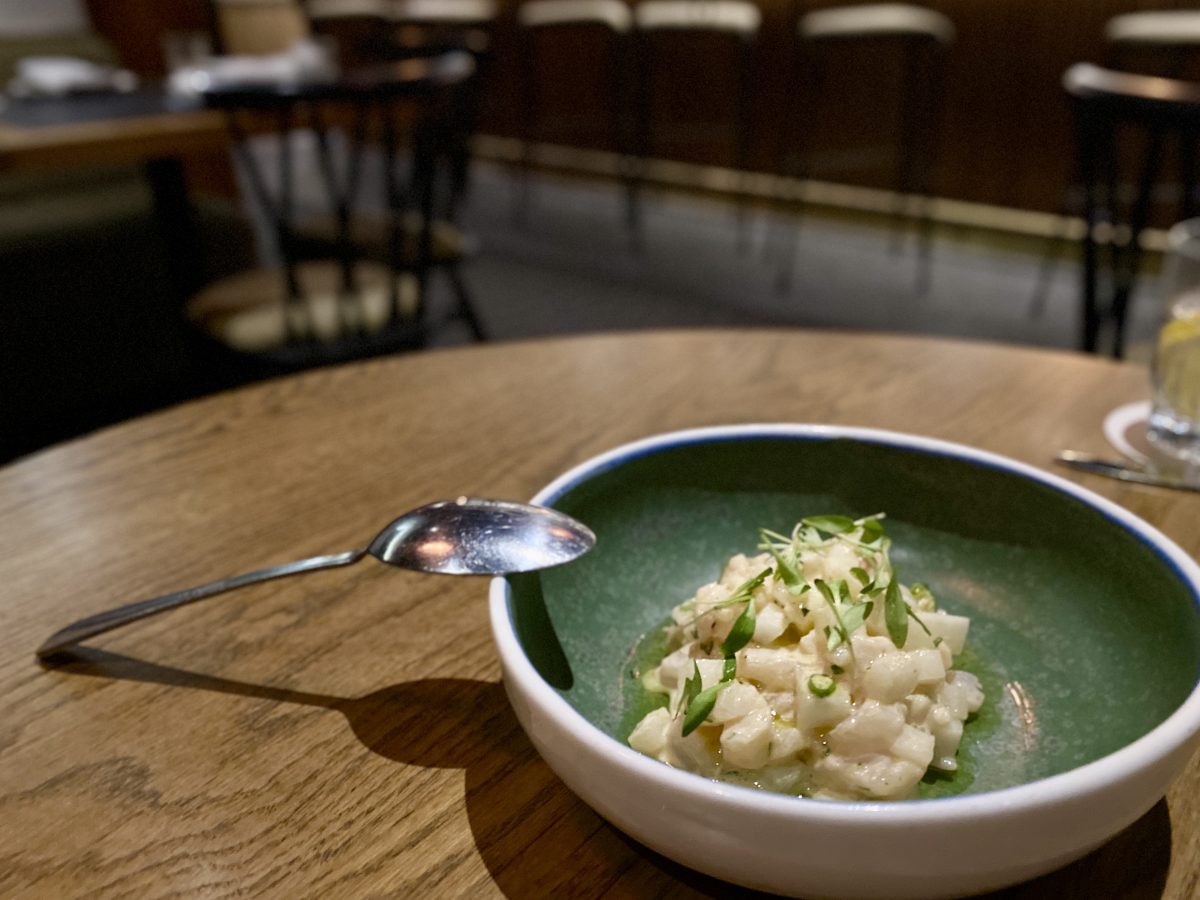 Green bowl with fish dish topped with herbs.