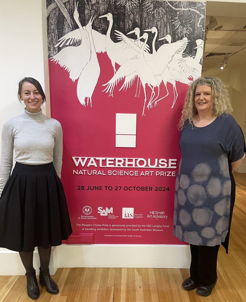 Two women in front of a sign saying Waterhouse Natural Science Art Prize