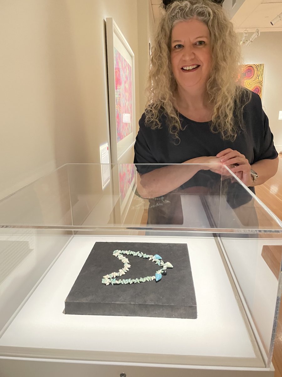 Woman leaning over glass cabinet with necklace inside