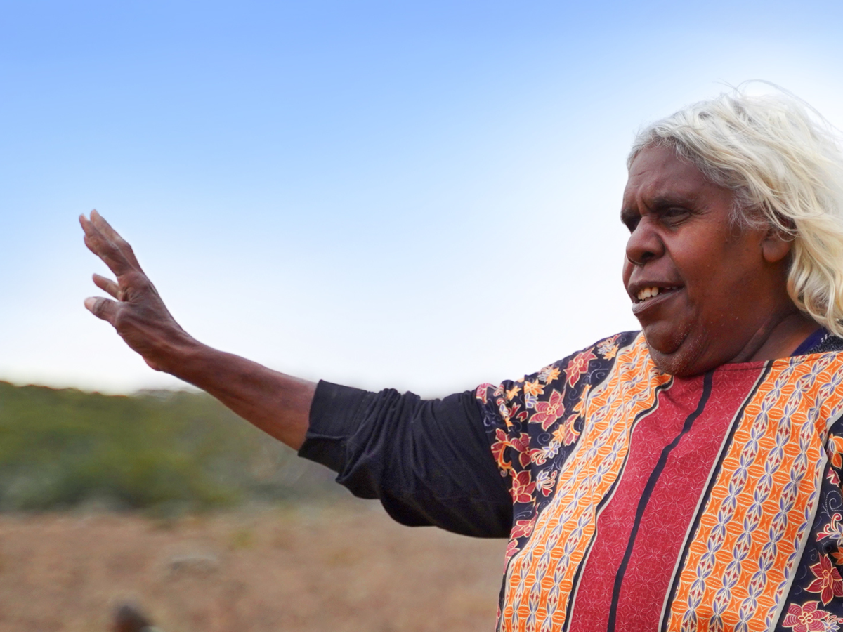 A woman in an Australian landscape holding up her hand