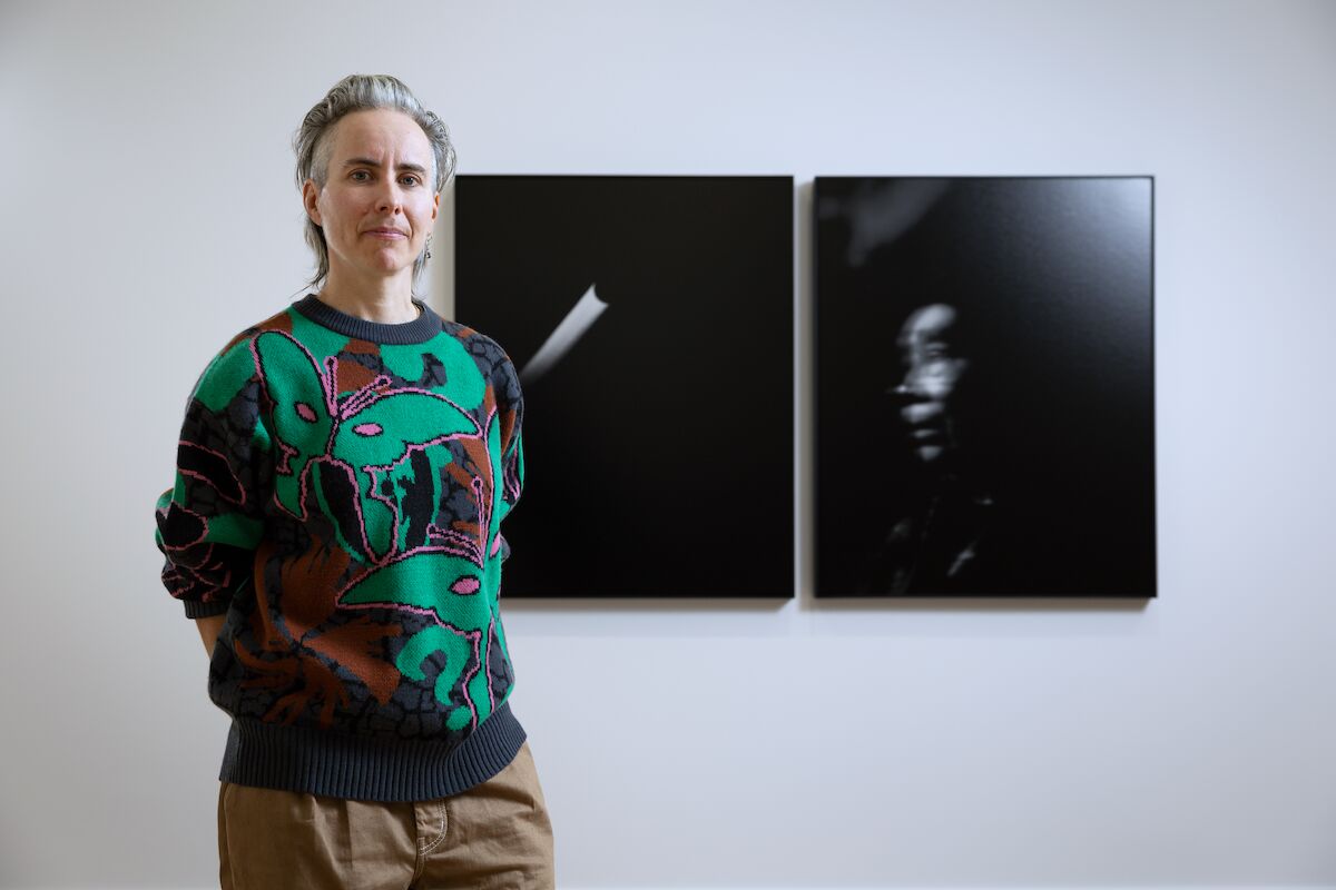 person stands next to two black and white photos