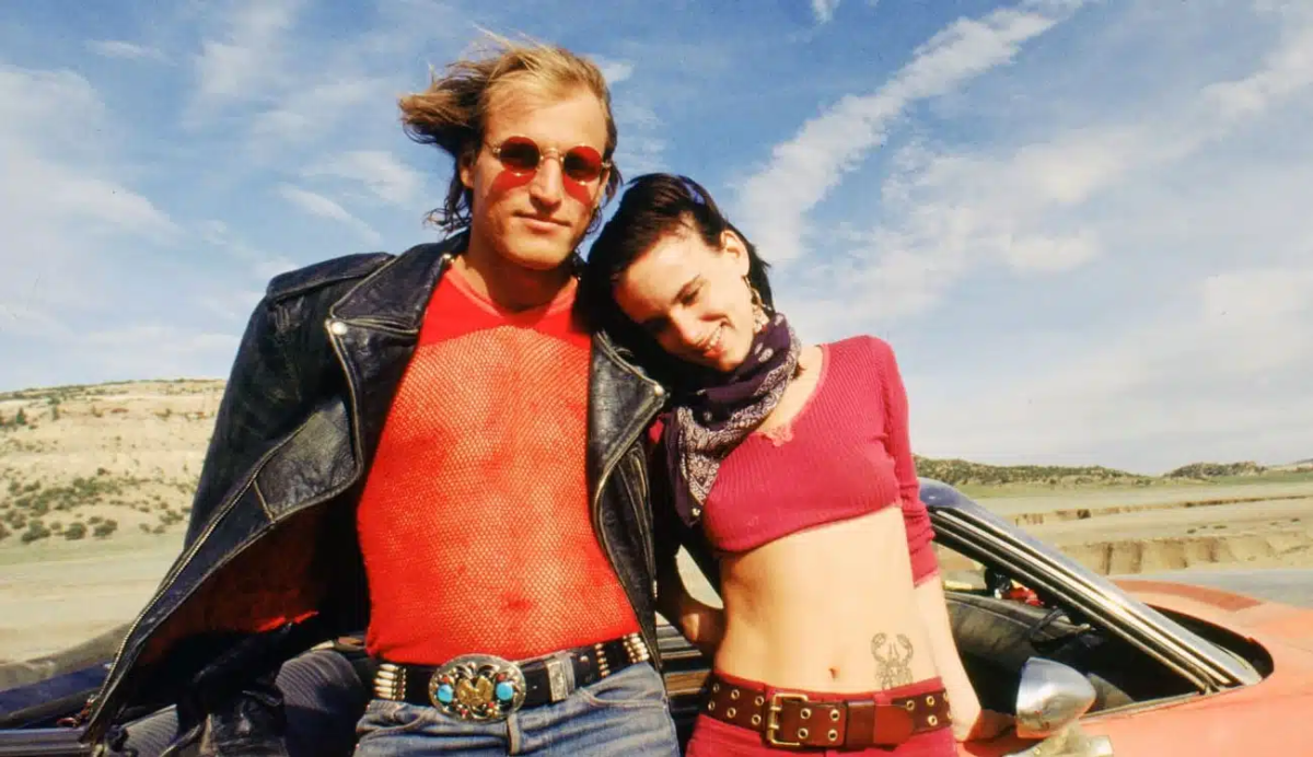 Still from Natural Born Killers showing a man and a woman leaning on a car