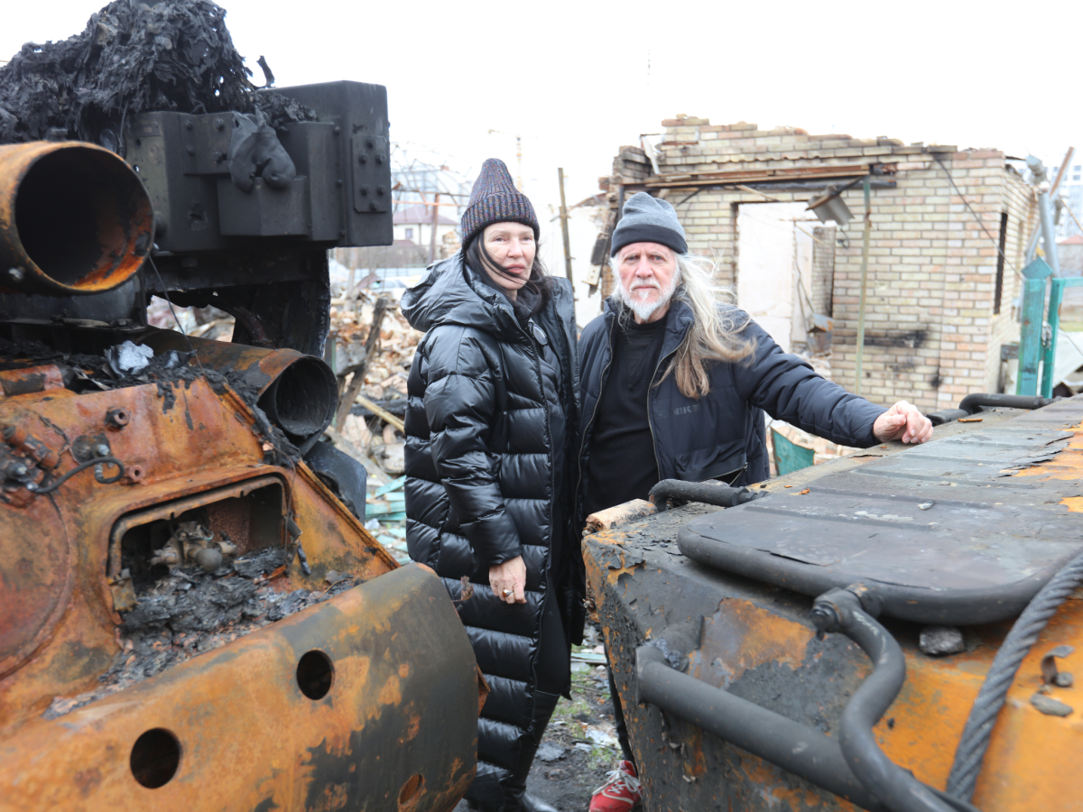 Two people in winter clothing standing amidst rubble in a street